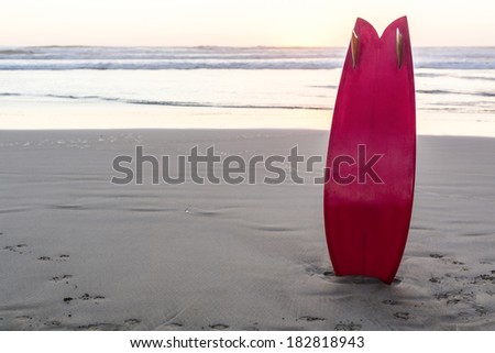 Red Retro Surfboard/ a retro styled surfboard standing on a west coast beach at sunset.