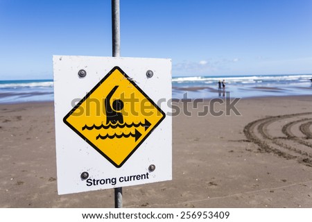 Strong Current/ a strong current warning sign on a beach.