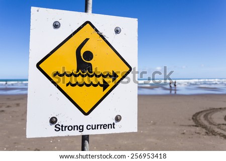 Strong Current/ a strong current warning sign on a beach.