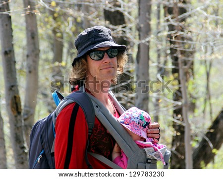 Young men hiking with little baby in the baby carrier in the spring forest  Portrait