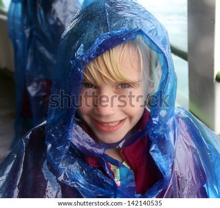 Happy little girl in blue raincoat. Niagara Falls boat trip.