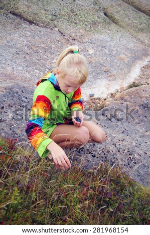 Blonde little girl gathering wild berries