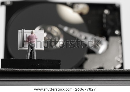 Big data concept-miniature engineer working with drafting table with open hard disk background
