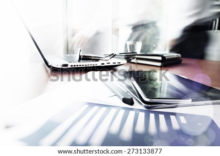 Abstract Image of business documents on office table with smart phone and digital tablet and man working in the background