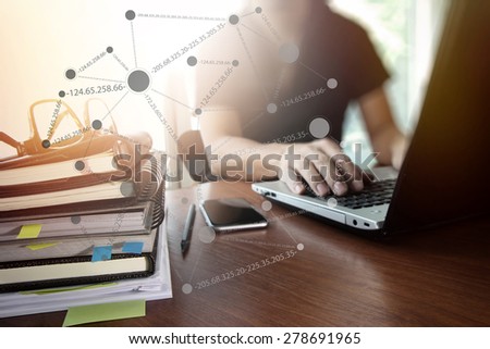 designer hand working with  digital tablet and laptop and notebook stack and eye glass on wooden desk in office