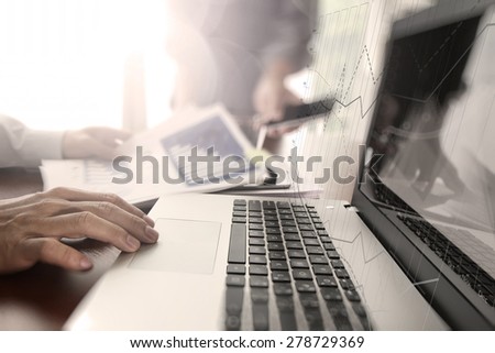 business documents on office table with smart phone and digital tablet and laptop computer and two colleagues discussing data in the background
