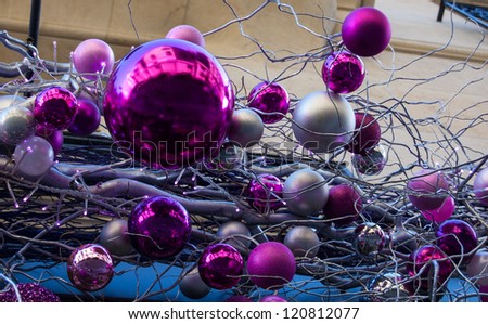 Violet and pink Christmas balls with street reflection. Silver twigs. Building at background. Paris.