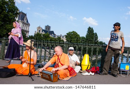 PARIS - JULY 6: Unidentified members of Hare Krishna play music and sing on the bridge near Louvre July 6, 2013 in Paris, France.