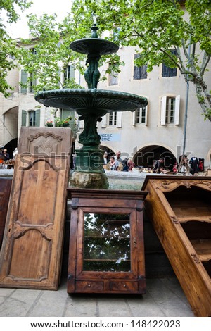 UZES, FRANCE - MAY 12: Antique wooden furniture leaning against the fountain at  flea market on May 12, 2013 in Uzes, France. Flea markets are very popular type of entertainment in France.