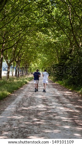 PARIS - JULY 13: Two unidentified young men jog in Vincennes forest on July 13, 2013 in Paris, France. Bois de Vincennes (Vincennes forest) is the largest park of Paris.
