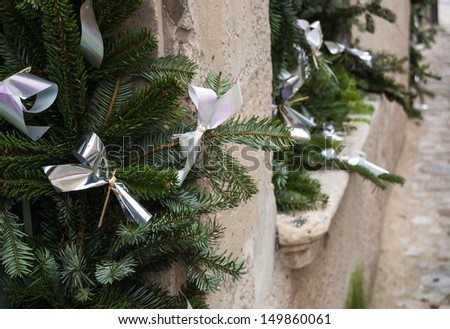 Christmas tree garlands with shiny bows in windows of old stone building. Medieval town Senlis, France.