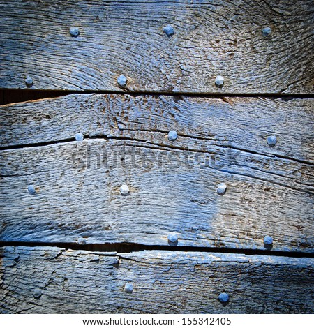 Old blue wooden texture with nail heads and cracks. Shadowed angles.