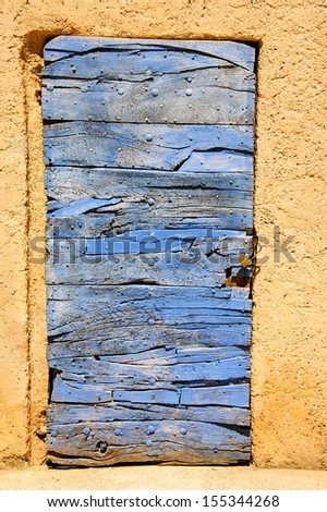 Old blue wooden door with nail heads and cracks. Abandoned house.