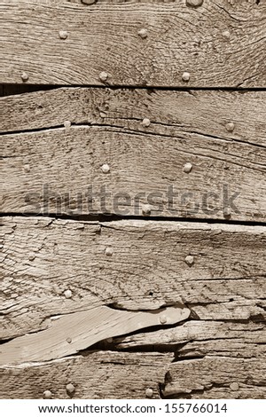 Old sepia wooden texture with nail heads and cracks.