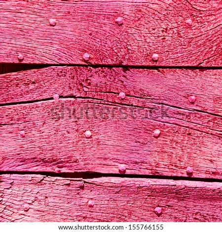 Old magenta wooden texture with nail heads and cracks.