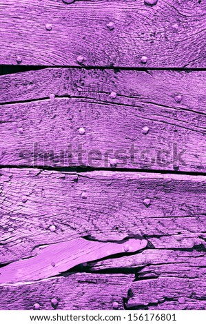 Old violet wooden texture with nail heads and cracks.