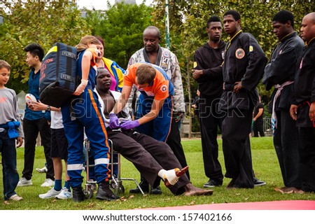 PARIS - SEPT 22: Volunteers of Civil Protection take care of Jiu-Jitsu performer who injured his leg during Famillathlon, action for raising awareness to sport on September 22, 2013 in Paris, France.