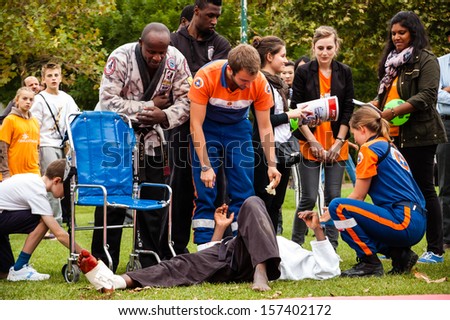 PARIS - SEPT 22: Volunteers of Civil Protection take care of Jiu-Jitsu performer who injured his leg during Famillathlon, action for raising awareness to sport on September 22, 2013 in Paris, France.