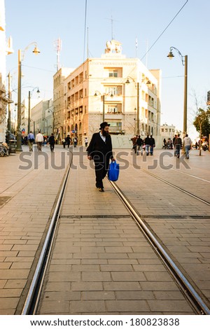 JERUSALEM, ISRAEL - FEBRUARY 19, 2014: Unidentified orthodox Jew walking on the rail of Light Rail tram train on Jaffa Road street. It operated since 2011 and serves up to 130,000 people every day.