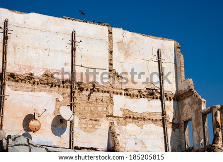 Old ruined house with two rusty satellite dishes and birds (pigeons) sitting over the wall. Nobody. Life is going on idea.