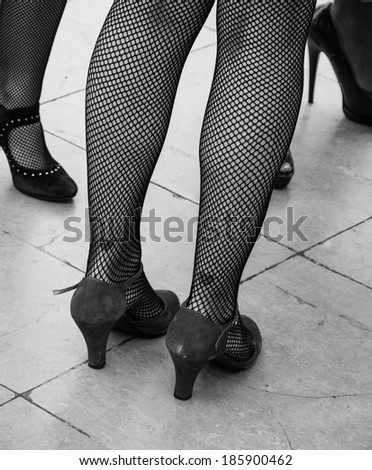 Retro style. Heart tattoo on sexy legs, vintage shoes and fishnet pantyhose. Aged photo. Black and white.