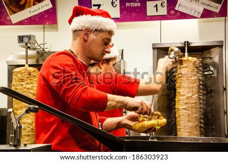 PARIS, FRANCE - NOVEMBER 30, 2013: Two unidentified men in Santa Claus hats cook and sell kebab at Christmas market.