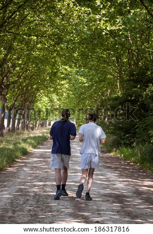 PARIS, FRANCE - JULY 13, 2013: Two unidentified young men jog in Vincennes forest. Bois de Vincennes (Vincennes forest) is the largest park of Paris.