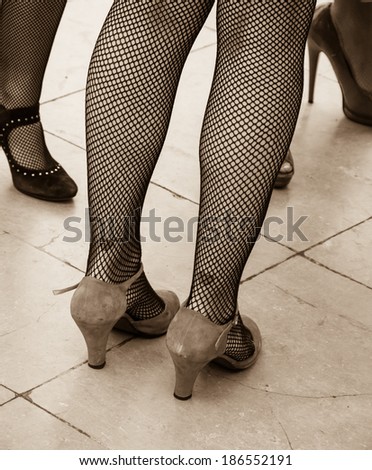 Retro style. Heart tattoo on sexy legs, vintage shoes and fishnet pantyhose. Aged photo. Sepia.