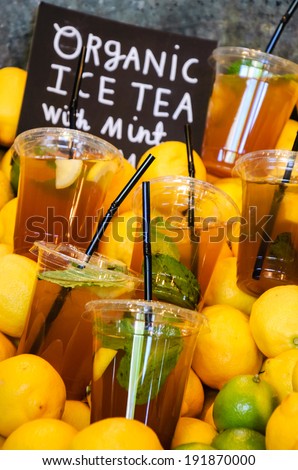 Fresh organic cold tea with lime, mint and lemon arranged in plastic cups with straw for sale  at Borough Market (London, England)