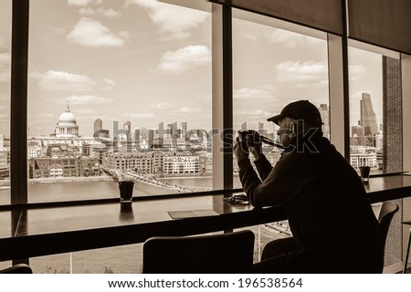 LONDON, ENGLAND, UK - MAY 3, 2014: Unidentified tourist takes picture of  a view on St Paul Cathedral from Tate Modern gallery\'s cafe.