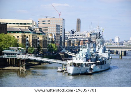 LONDON, ENGLAND, UK - MAY 3, 2014: HMS Belfast (Royal Navy light cruise) - warship Museum in London and cityscape. Belfast moored in London on River Thames and operated by the Imperial War Museum.