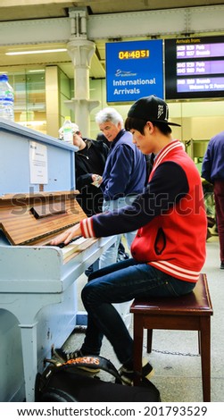 LONDON, ENGLAND, UK - MAY 2, 2014:  Young man playing piano near the Eurostar arrivals gate at St Pancras International Station. Street Pianos Project encourages people playing music in public places.