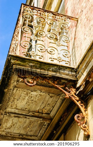 Old balcony. Rusty wrought iron railing with floral curling pattern. Weathered wooden base with peeling paint. Mers-les-Bains (Picardy, France)