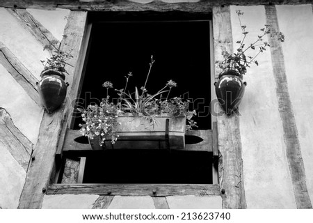 Old half timbered house house decorated with flowers.  Dol de Bretagne, Brittany, France. Aged photo. Black and white.
