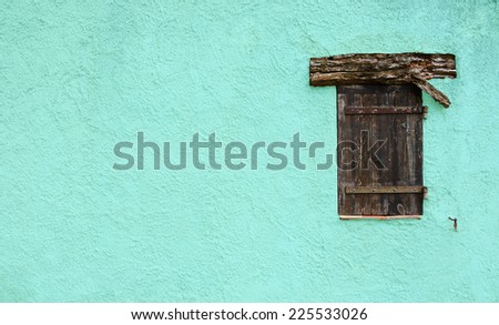 Old typical Mediterranean house with cyan stucco wall and closed wooden shutters.