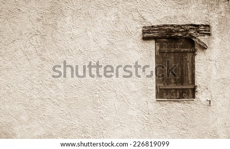 Old typical Mediterranean house with stucco wall and closed wooden shutters. Aged photo. Sepia.