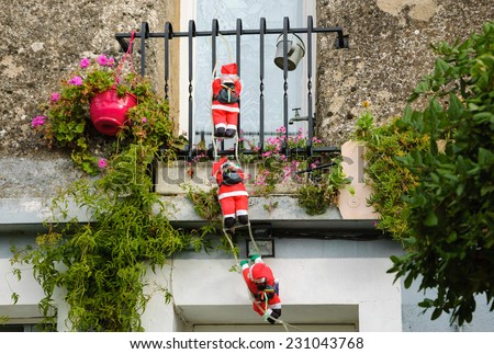Three Santa Claus figures climbing up a wall into a window. Traditional Christmas decoration.