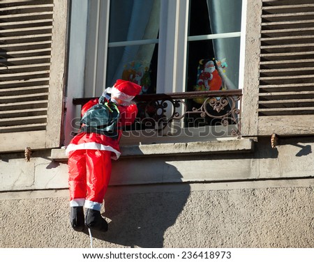 Santa Claus climbing up a wall into a window. Traditional Christmas decoration.