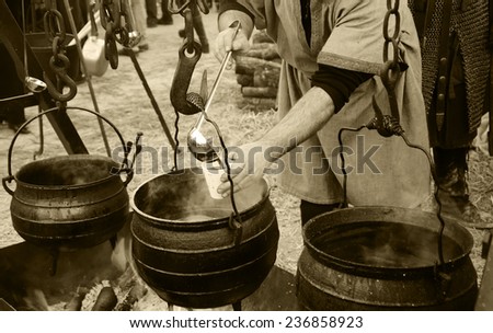 Man prepares and sells hot wine and soup at traditional Christmas Medieval fair in Provins (France). Aged photo. Sepia.