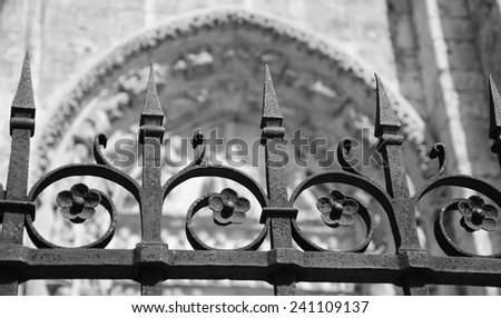 Forging fence of Cathedral in Chartres (France). Selective focus on the arrows of the fence. Aged photo. Black and white.