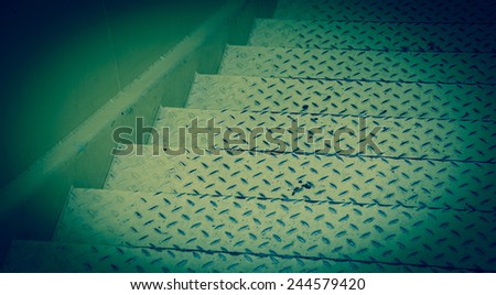 Yellow steel diamond plate stairs and yellow concrete wall. Blue toned photo.