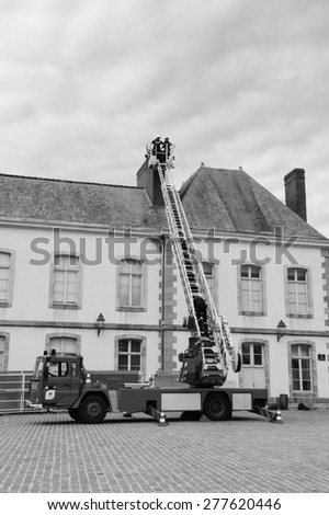 VITRE, FRANCE - JULY 12, 2014: Firemen carry out training exercise near a building at castle square of Vitre. According to statistics there are more than 83,000 residential fires every year in France.