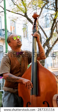 LISBON, PORTUGAL - APRIL 22, 2015: Unidentified street musician in sunglasses performs before the tourists and citizens at city square.