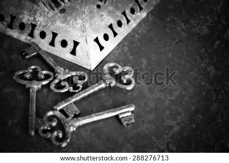Jewelry box and four vintage keys. Retro aged toned photo with scratches. Black and white. Vignette.
