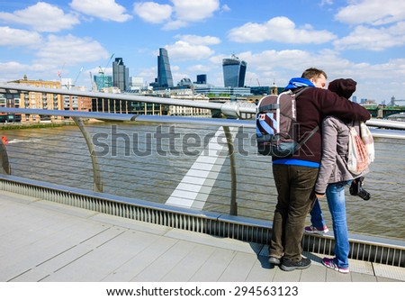 LONDON, ENGLAND, UK - MAY 3, 2014: Unidentified tourists looking on the cityscape from Millennium Bridge. Millennium Bridge, which linking Bankside with the City of London, was opened in 2000.