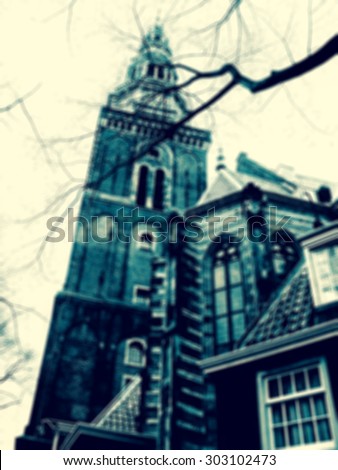 Oude Kerk (Old Church) in Amsterdam (Netherlands) seen through the bare tree twigs. Blurred toned photo.