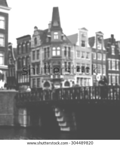 Amsterdam houses and bridge over the canal in cloudy day. Blurred aged photo. Black and white.