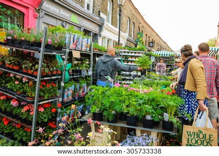 LONDON, ENGLAND, UK - MAY 4, 2014: People buying plants and  flowers at Columbia Road Flower Market. This London's principal flower market is opened every Sunday.