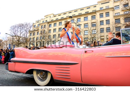 PARIS, FRANCE - JANUARY 1, 2015: Beauty queens, driving in old pink car, participate in New Year Parade on Avenue des Champs-Elysees. New Year Parade is annual event.