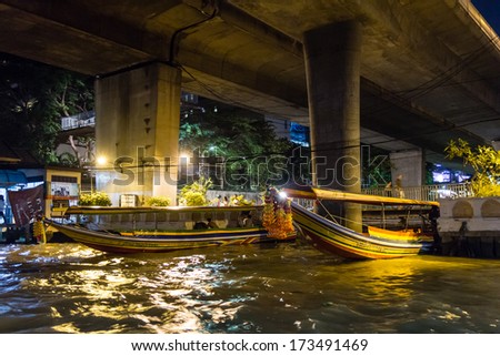 BANGKOK - NOVEMBER 1, 2013 - Boat captains tie their longtail tourist boats for the night under a bridge on Chao Phraya River in Bangkok circa November 2013. Bangkok is a popular tourist destination.